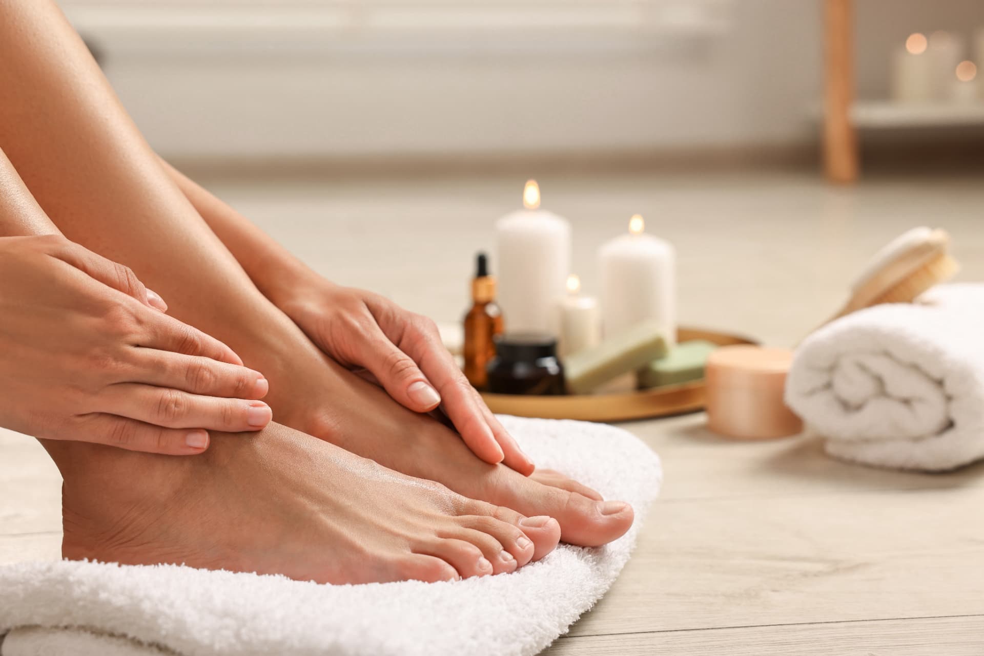 Client's feet resting on a soft towel with candles and foot care products during a home foot health treatment in Hertfordshire